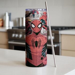 K&ouml;nnte beinhalten: Ein hoher, zylindrischer Becher mit einem Spider-Man-Comic-Design. Der Becher zeigt den Superhelden in seinem ikonischen rot-schwarzen Anzug mit einem schwarzen Spinnenemblem. Ein silberfarbener Metallstrohhalm befindet sich neben dem Becher.
