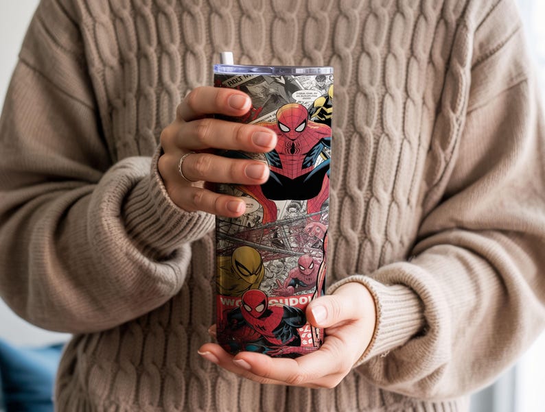 K&ouml;nnte beinhalten: Ein hoher, isolierter Becher mit einer Collage aus Spider-Man-Comics. Das Design zeigt Spider-Man in verschiedenen Posen, mit einem rot-schwarzen Farbschema. Der Becher hat einen silbernen Deckel und einen wei&szlig;en Strohhalm.