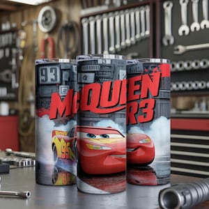 Pu&ograve; includere: Tre bicchieri cilindrici con la grafica dell'auto da corsa rossa Lightning McQueen. Il design include il testo "MCQUEEN" in grassetto rosso, il numero 95 e uno sfondo che raffigura un garage con attrezzi e componenti meccanici.