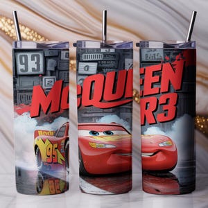 Pu&ograve; includere: Tre bicchieri cilindrici con coperchi e cannucce in metallo che presentano una grafica di auto da corsa rossa, il numero 95 e il testo McQueen. Il design include uno sfondo grigio scuro con dettagli meccanici ed effetti di fumo.