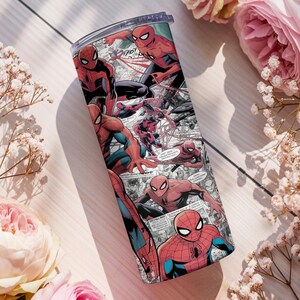 K&ouml;nnte beinhalten: Ein Edelstahlbecher mit einem Comic-Design von Spider-Man. Das Design zeigt Spider-Man in Rot und Blau mit schwarzen Akzenten in verschiedenen Actionposen. Der Becher hat einen transparenten Deckel.