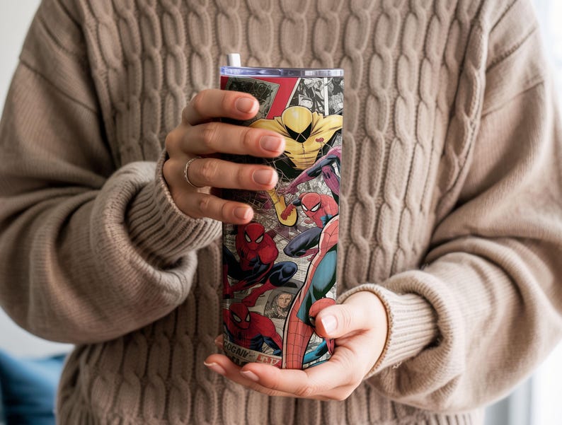 K&ouml;nnte beinhalten: Ein hoher, isolierter Becher mit einem Comic-Design mit Spider-Man und anderen Charakteren. Der Becher hat einen schwarzen Deckel und einen wei&szlig;en Strohhalm. Das Design umfasst rote, blaue, gelbe und schwarze Farben.