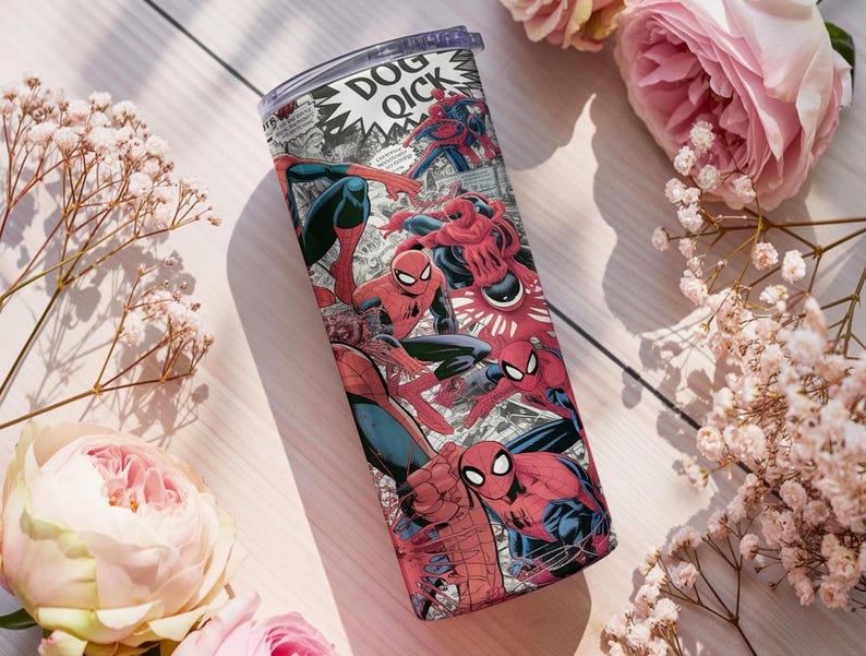 K&ouml;nnte beinhalten: Ein Edelstahlbecher mit Comic-Design, der Spider-Man-Illustrationen in Rot, Blau und Schwarz zeigt. Der Becher hat einen transparenten Deckel. Er ist von rosa Rosen und wei&szlig;en Blumen umgeben.