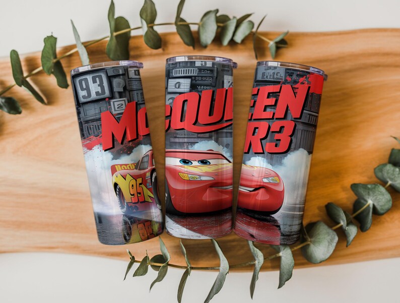 Pu&ograve; includere: Tre bicchieri cilindrici con la grafica di un'auto da corsa rossa con il numero 95, il testo McQueen e uno sfondo di luci da stadio. Il design presenta una finitura metallica, un coperchio trasparente e una tavolozza di colori rosso, nero e grigio.