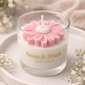 Könnte beinhalten: Eine Kerze in einem Glas mit einem rosa Blüten-Design. Die Kerze hat eine weiße Wachsbasis und ist mit "Anna & Mark" und dem Datum "20.07.2024" beschriftet. Die Kerze steht auf einem weißen Teller.