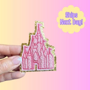 May include: Pink castle patch with gold glitter trim. The castle design is embroidered with a detailed outline. The background is a gradient of yellow, pink, and purple. The text "Ships Next Day!" is in a yellow bubble.