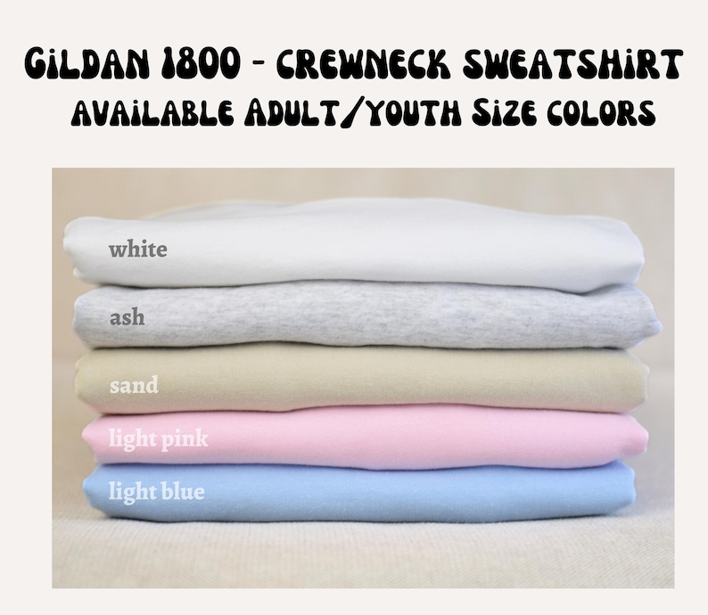 A stack of five different colored crew neck sweatshirts, with each color labeled: white, ash, sand, light pink, and light blue.