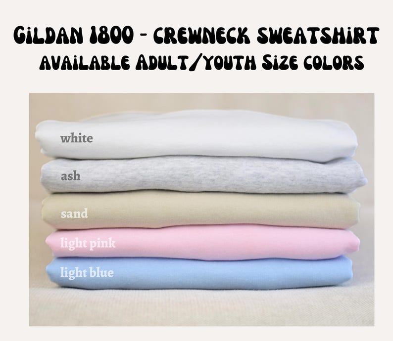 A stack of five different colored crew neck sweatshirts, with each color labeled: white, ash, sand, light pink, and light blue.