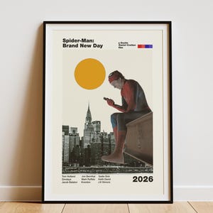 May include: A framed poster titled Spider-Man: Brand New Day featuring a graphic of a figure in a red and blue suit sitting on a ledge overlooking a black and white cityscape. A large yellow circle sits above the figure, with text listing cast names and the year 2026 at the bottom.