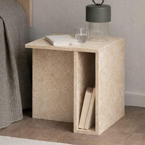May include: A light beige, modern nightstand with a built-in shelf. A glass of water, a book, and a decorative lamp with a dark green top and a clear, ribbed glass base sit on top. Two books are in the shelf.