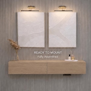 Peut inclure: Deux tableaux muraux rectangulaires blancs texturés avec des lampes dorées montées au-dessus. En dessous, une console flottante en bois clair est fixée sur un mur à rainures verticales. Le texte READY TO MOUNT Fully Assembled est visible.