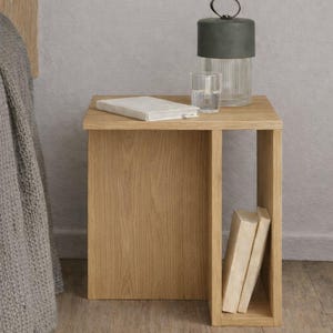 May include: A light oak bedside table with a rectangular top and an open shelf. A green and clear glass lamp, a glass of water, and a book are on the table. Two books are in the open shelf.