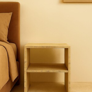 May include: A light-colored, two-tiered wooden nightstand with a rectangular frame. The nightstand is placed next to a bed with a brown headboard and bedding. The background is a solid, light-yellow color.