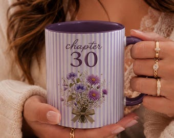 May include: A ceramic mug with a light purple and white vertical striped pattern. The front features the text "chapter 30" in a dark purple script and print font, positioned above a bouquet of purple and blue flowers tied with a green ribbon.