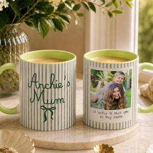 Peut inclure: Deux mugs en c&eacute;ramique avec des anses et des bords verts. L'un des mugs porte l'inscription "Archie's Mum" et un n&oelig;ud. L'autre mug porte une photo d'une femme et d'un enfant avec l'inscription "So lucky to have you as my mama". Les deux mugs ont un motif &agrave; rayures verticales.
