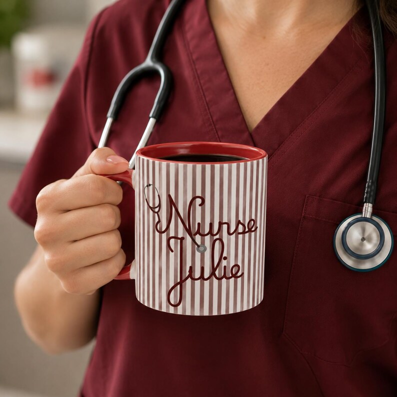 May include: A red and white striped coffee mug with the words "Nurse Julie" in a cursive font. The mug has a red interior and handle. A stethoscope hangs in the background.