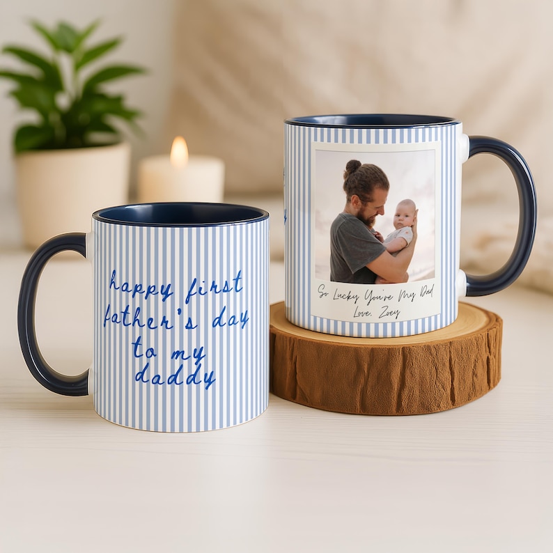 May include: Two white ceramic mugs with blue pinstripes and navy blue accents. One mug has the text "happy first father's day to my daddy" in blue script. The other mug has a photo and the text "So Lucky You're My Dad Love, Zoey".