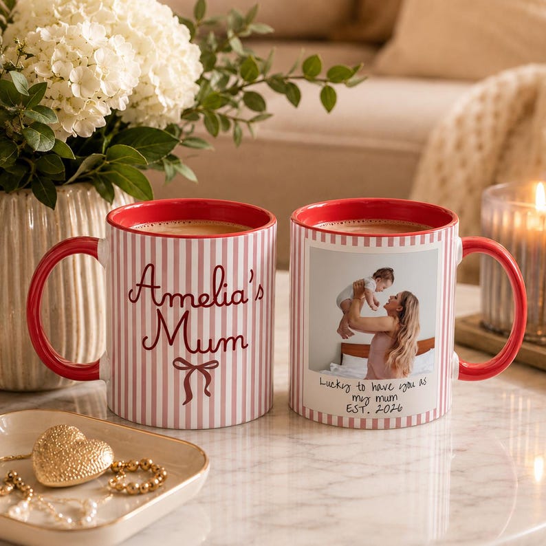 Peut inclure: Deux mugs en c&eacute;ramique avec des anses et des bords rouges. L'un des mugs porte l'inscription "Amelia's Mum" en &eacute;criture cursive avec un n&oelig;ud. L'autre mug pr&eacute;sente une photo d'une m&egrave;re et d'un enfant avec le texte "Lucky to have you as my mum EST. 2026". Les deux mugs ont un motif &agrave; rayures.