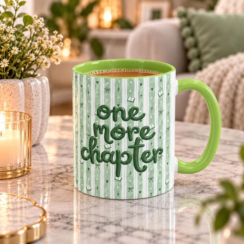 May include: A ceramic mug with a light green and white vertical striped pattern featuring the dark green text one more chapter, small book icons, and bow illustrations. The mug has a solid light green interior and a matching light green handle.