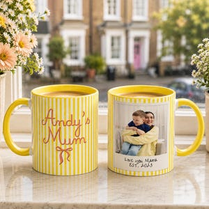 Peut inclure: Deux mugs jaunes &agrave; rayures verticales. L'un porte l'inscription "Andy's Mum" en rose. L'autre mug pr&eacute;sente une photo d'une m&egrave;re et d'un enfant avec le texte "Love you Mama EST. 2023".