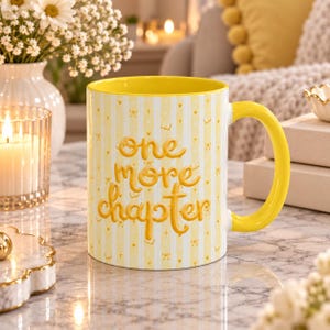 May include: A yellow ceramic mug with a bright yellow interior and handle. The exterior features a light yellow and white vertical striped pattern with small gold icons and the embossed text "one more chapter" in a rounded yellow font.
