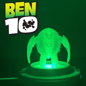 Pode incluir: Uma figura verde brilhante da série animada Ben 10, iluminada por baixo, está sobre uma base circular. O logotipo Ben 10, com as palavras "BEN" e o número "10", está no canto superior esquerdo. O fundo é verde escuro.