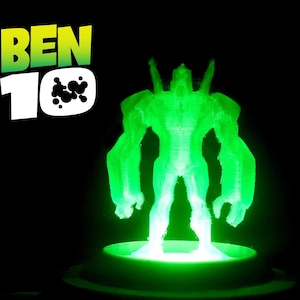 Könnte beinhalten: Eine leuchtend grüne Figur aus der Ben 10-Serie, vor einem schwarzen Hintergrund. Die Figur steht auf einer kreisförmigen Basis und strahlt hellgrünes Licht aus. Das Ben 10-Logo ist oben links zu sehen.