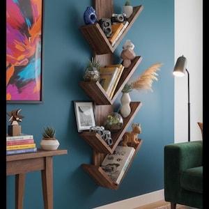 Op de afbeelding: Een donkerhouten, boomvormige boekenplank aan een blauwgroene muur, gevuld met boeken, decoratieve vazen en kleine objecten. Een ingelijst abstract schilderij en een bijzettafel met boeken en een plant zijn ook zichtbaar.