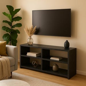 May include: A modern living room setup featuring a black TV mounted on a beige wall above a black media console. The console holds books, decorative vases, and a geometric sculpture. A sofa, plant, and coffee table complete the scene.