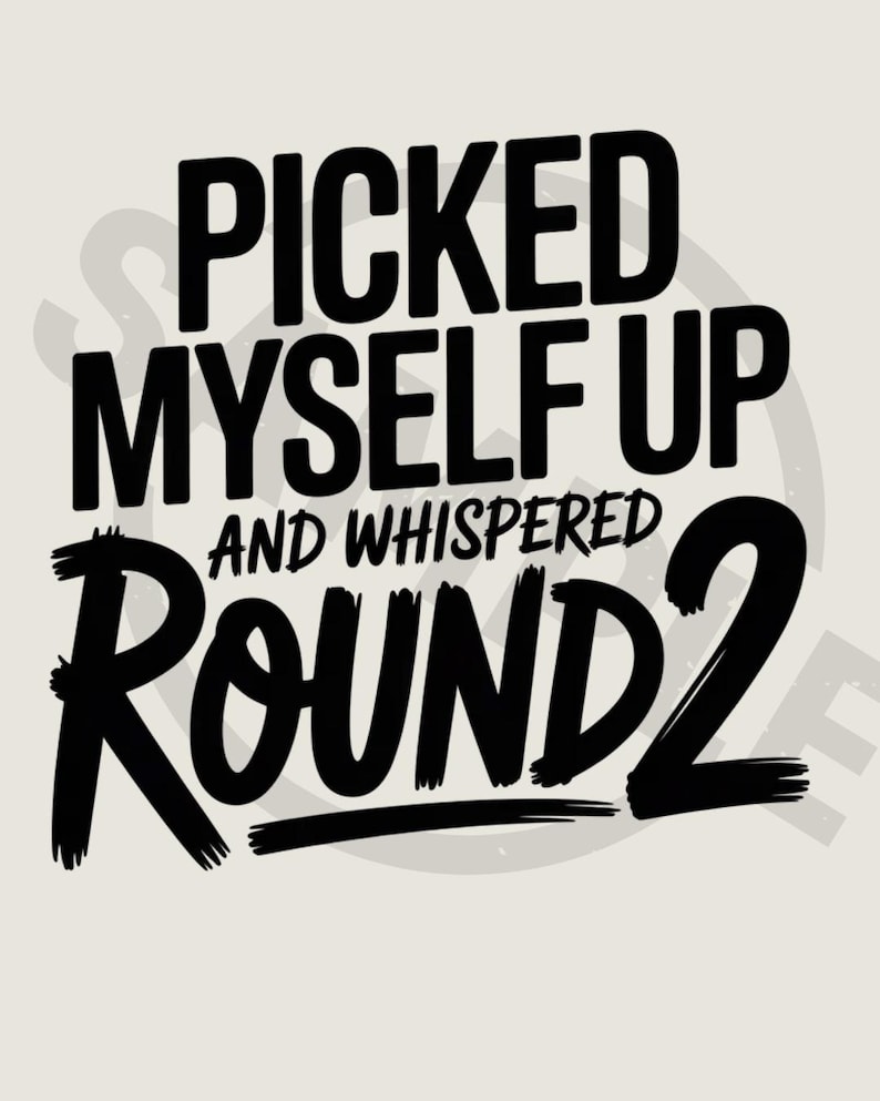May include: A motivational graphic featuring the phrase "PICKED MYSELF UP AND WHISPERED ROUND 2" in bold black text. The words are stacked on a light beige background, with a faint circular design behind the text.