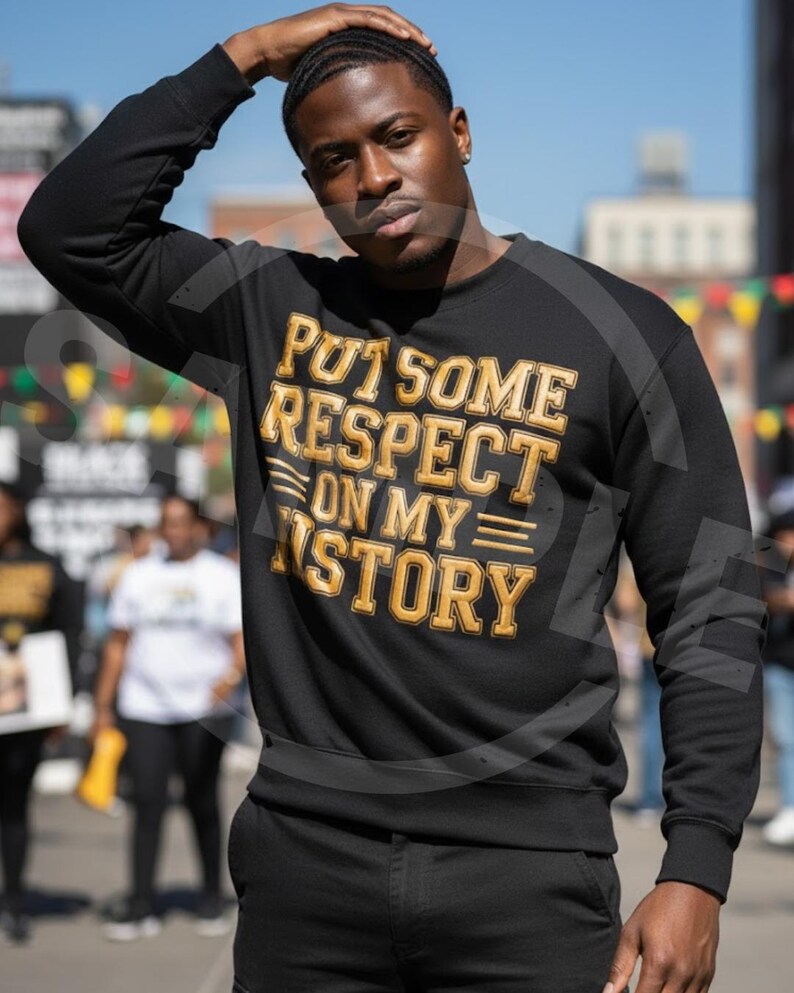 May include: Black sweatshirt with the text "PUT SOME RESPECT ON MY STORY" in gold and white lettering. The sweatshirt is a crew neck style. The person in the image is wearing the sweatshirt.