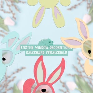 May include: Easter window decorations with bunny shapes in pastel shades of blue, yellow, and pink. The text "EASTER WINDOW DECORATIONS osterhase fensterbild" is displayed on a light green background.