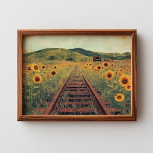 May include: A framed print featuring a rustic railway track receding into the distance, flanked by a field of vibrant yellow sunflowers. Rolling green hills and a vintage train car are visible in the background, under a soft, cloudy sky.