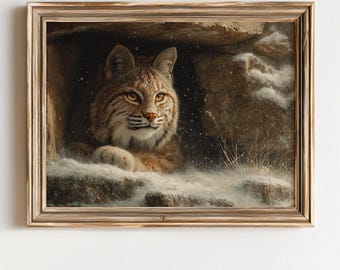 May include: A framed painting of a bobcat resting in a snowy cave. The bobcat has brown and tan fur with orange eyes and is looking to the right. The painting has a gold-colored frame and is set against a white background.