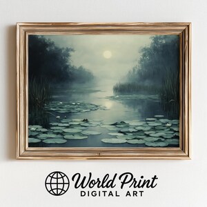 May include: A framed landscape painting depicts a serene lake scene under a moonlit sky. The artwork features water lilies, tall reeds, and trees along the water's edge, all rendered in muted blues and greens. The frame is a warm gold color.