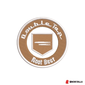 Könnte beinhalten: Gestickter Aufnäher mit einem braunen kreisförmigen Design und weißem Text. Der Text lautet "Double Tap" am äußeren Rand und "Root Beer" unten. Eine schildförmige Grafik befindet sich in der Mitte.