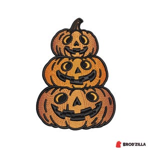Puede incluir: Un parche bordado que muestra una pila de tres calabazas de Halloween naranjas con contornos y rasgos faciales cosidos en negro. Cada calabaza tiene una sonrisa tallada y una nariz triangular. El texto BROD'ZILLA aparece abajo a la derecha.