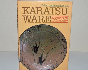 May include: A book titled "KARATSU WARE" by Johanna Becker, O.S.B. The cover is tan with brown text and a circular image of a ceramic plate with a floral design. The subtitle reads "A Tradition of Diversity."