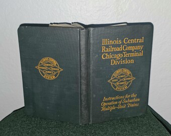 Puede incluir: Un libro de tapa dura de color verde oscuro titulado Illinois Central Railroad Company Chicago Terminal Division Instructions for the Operation of Suburban Multiple-Unit Trains, con texto dorado y un logotipo circular en las portadas.