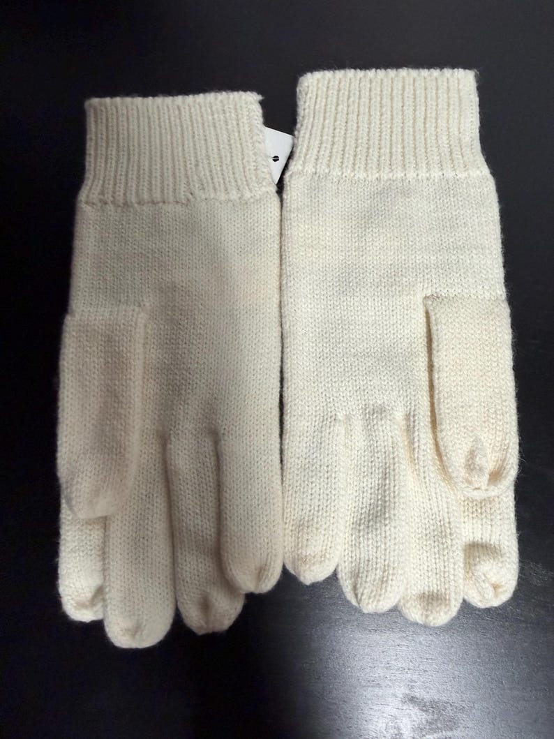May include: A pair of ivory-colored knitted gloves. The gloves have a ribbed cuff and a separate section for each finger. The material appears to be a soft, warm knit, suitable for cold weather.