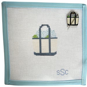 May include: Needlepoint canvas with a light blue border. The canvas features a stitched design of a tote bag with a light blue handle and a small pin of a tote bag with a needle. The initials "sSc" are stitched in the bottom right corner.