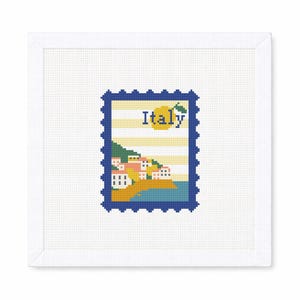 May include: A cross-stitch design of an Italian postage stamp. The stamp features a coastal scene with colorful buildings, a yellow lemon, and the word "Italy" in blue. The stamp is framed in a blue border.