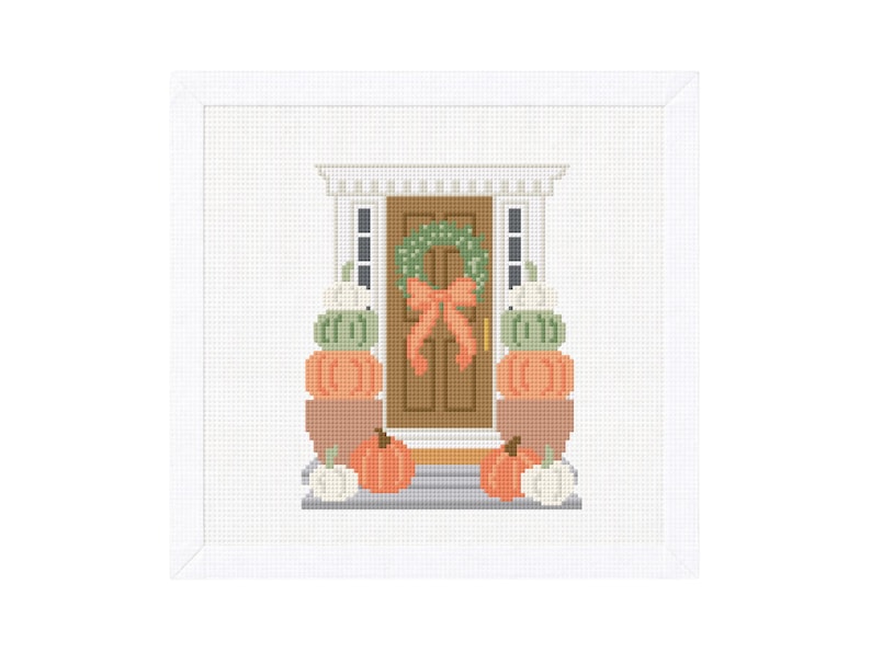 Op de afbeelding: Een kruissteekontwerp van een voordeur versierd voor de herfst. De bruine deur heeft een groene krans en een oranje strik. Stapels pompoenen in oranje, groen en wit flankeren de deur, wat een herfstige sc&egrave;ne cre&euml;ert.