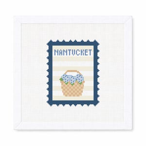 Puede incluir: Un diseño de punto de cruz con un borde de sello postal azul marino, con la palabra "NANTUCKET" y una cesta de flores azules. El fondo tiene rayas azules y blancas. El diseño está sobre un fondo blanco.