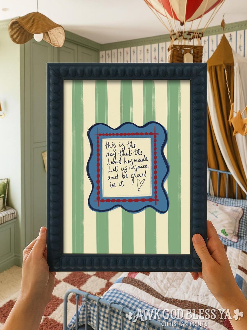 May include: A framed wall art print featuring a light green and cream vertical striped background. In the center, a blue wavy-edged frame surrounds a cream-colored square with the handwritten text: This is the day that the Lord has made.