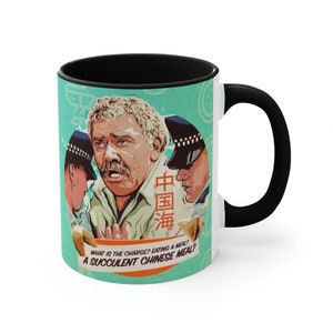 May include: White ceramic mug with a black handle and rim. The mug features a colourful illustration of a man being arrested by two police officers. The text on the mug reads "WHAT IS THE CHARGE? EATING A MEAL? A SUCCULENT CHINESE MEAL?"