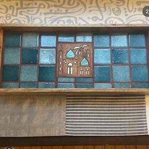 May include: A rectangular wooden serving tray featuring a mosaic of glossy teal and blue square tiles. The center tile displays a detailed terracotta-colored relief illustration of a building with domes, arches, and a palm tree.