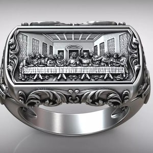 Può includere: Un anello color argento con un rilievo dettagliato dell'Ultima Cena. La faccia rettangolare dell'anello mostra la scena biblica all'interno di un bordo ornato e a volute. La fascia dell'anello è liscia e lucida.