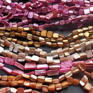 Pode incluir: Conjunto de contas de concha iridescente em vários tons de rosa, marrom e dourado. As contas são quadradas e têm um acabamento liso e polido.