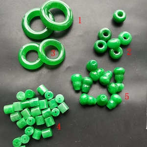 May include: Assortment of green jade beads in various shapes and sizes, including round, cylindrical, and gourd-shaped beads. The beads are arranged in groups labeled 1 through 5.